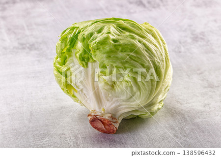 Fresh whole head of iceberg lettuce with crisp green leaves on a light gray concrete background. Fresh whole head of iceberg lettuce with crisp green leaves on a light gray concrete background. 138596432