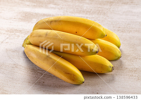 Bunch of ripe yellow bananas on a rustic textured surface Bunch of ripe yellow bananas on a rustic textured surface 138596433