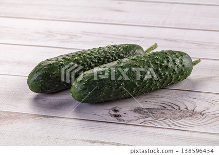 Two fresh green bumpy cucumbers on a light wooden background. Two fresh green bumpy cucumbers on a light wooden background. 138596434