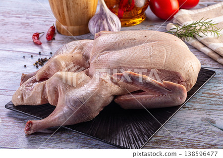 Raw whole duck on a black plate with fresh herbs and spices for cooking Raw whole duck on a black plate with fresh herbs and spices for cooking 138596477