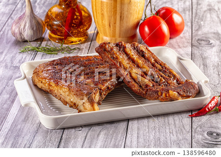 Savory grilled pork ribs served on a white platter with fresh ingredients Savory grilled pork ribs served on a white platter with fresh ingredients 138596480