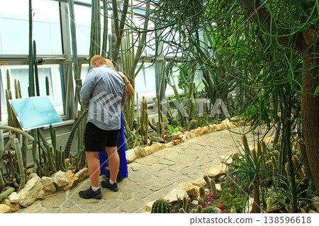 Visitors to the botanical garden examine plants. Young couple observes plants Visitors to the botanical garden examine plants. Young couple observes plants 138596618