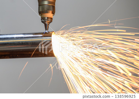 Close-up of a high-precision fiber laser cutting machine engraving a stainless steel tube with bright sparking light. 138596925