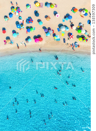 Aerial view of colorful umbrellas on sandy beach, swimming people 138597309