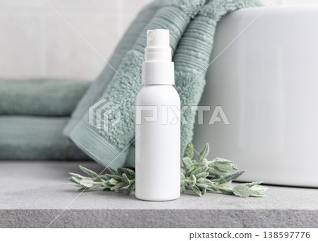 White spray bottle mockup near leaves light green towel in bathroom. Unbranded cosmetic White spray bottle mockup near leaves light green towel in bathroom. Unbranded cosmetic 138597776