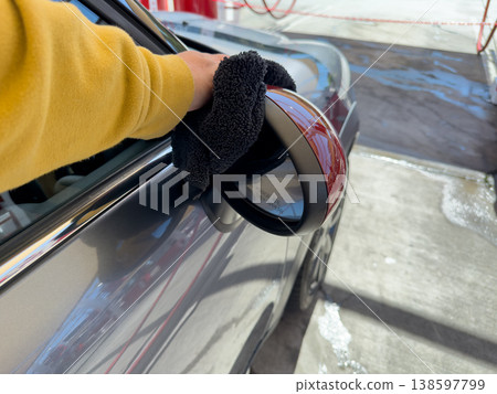 Man wiping and drying car with grey microfiber rag outdoors, closeup 138597799