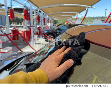Man wiping and drying car with grey microfiber rag outdoors, closeup 138597817