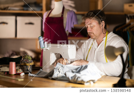 Middle-aged male dressmaker working with sewing-machine 138598548