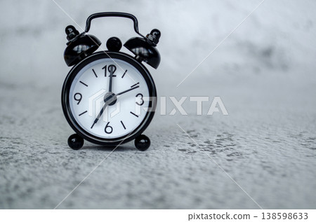 Clean black alarm clock thumbnail presenting a seven o clock morning time setting against a soft neutral surface backdrop Clean black alarm clock thumbnail presenting a seven o clock morning time setting against a soft neutral surface backdrop 138598633