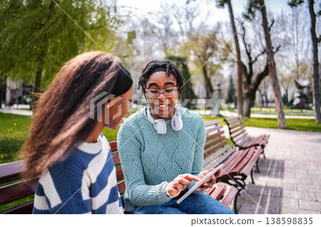 Young adult female friends sharing content on digital tablet in park Young adult female friends sharing content on digital tablet in park 138598835