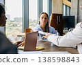 Woman Reviewing Documents. Woman Concentrates On Report While Coordinator Offers Approval Documents Nearby 138598843