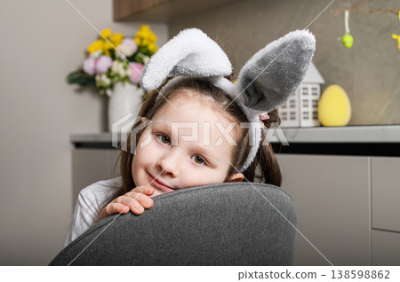 Cute girl in bunny ears leaning on chair in kitchen interior 138598862