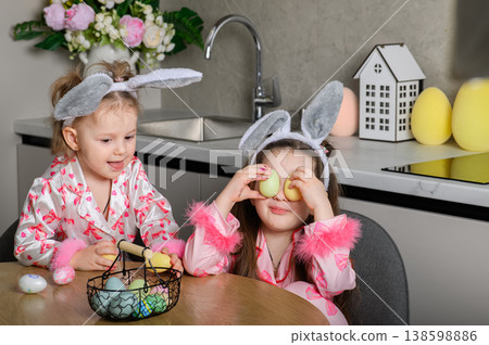 Two girls painting Easter eggs at table in kitchen Two girls painting Easter eggs at table in kitchen 138598886