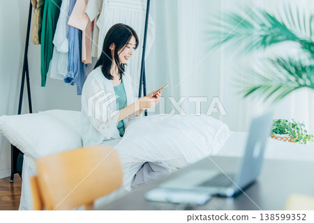 少婦在床上的看智能手機 138599352