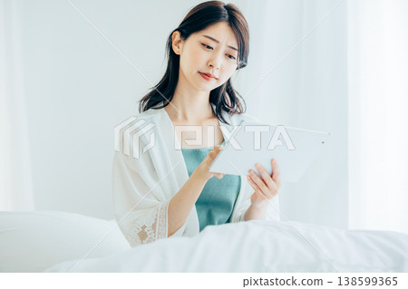 A middle-aged woman operating a tablet in bed A middle-aged woman operating a tablet in bed 138599365