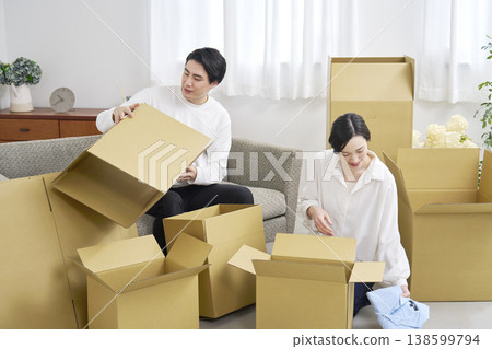A couple sorting through cardboard boxes during a move. A couple sorting through cardboard boxes during a move. 138599794