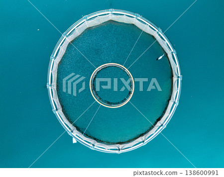 Aerial view of a fish farm with floating cages arranged on the water surface. Modern aquaculture and sustainable seafood production. 138600991