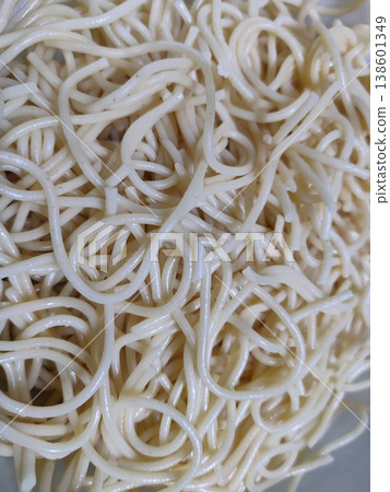 Close-up Image of Cooked Noodles Showing Twisted and Wavy Shapes Glistening in Natural Light on a White Plate Surface Close-up Image of Cooked Noodles Showing Twisted and Wavy Shapes Glistening in Natural Light on a White Plate Surface 138601349