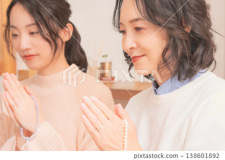A mother and daughter praying for the deceased at home (retro style) A mother and daughter praying for the deceased at home (retro style) 138601892