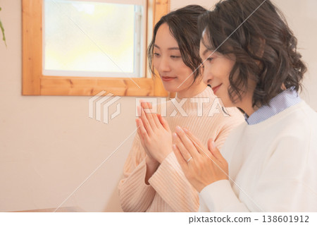 A mother and daughter praying for the deceased at home (retro style) A mother and daughter praying for the deceased at home (retro style) 138601912