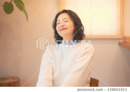 A middle-aged woman (in a retro style) after offering prayers for the deceased at home. A middle-aged woman (in a retro style) after offering prayers for the deceased at home. 138601923