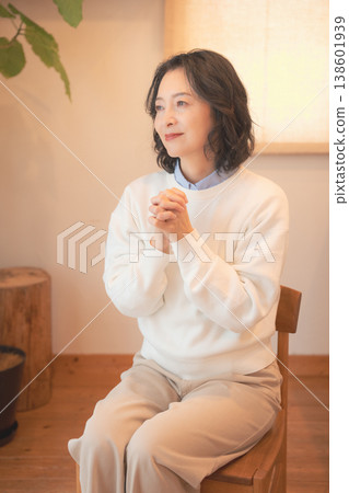 A middle-aged woman (in a retro style) offers prayers for a deceased loved one at home. 138601939