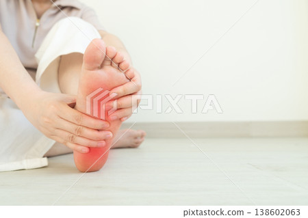 Female suffering from foot pain or numbness at home. Causes of pain include plantar fasciitis, gout, arthritis, tendinitis, diabetic neuropathy or overuse injuries. 138602063