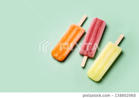 Colorful fruit popsicles on green background Colorful fruit popsicles on green background 138602068