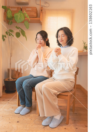 A mother and daughter praying for the deceased at home (retro style) A mother and daughter praying for the deceased at home (retro style) 138602163