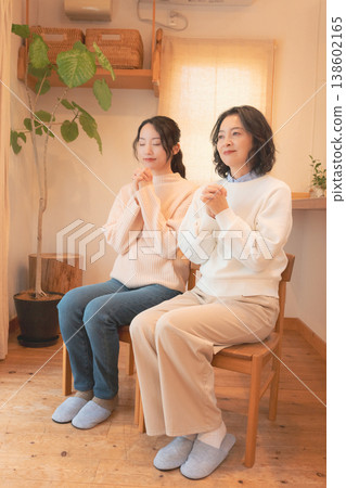 A mother and daughter praying for the deceased at home (retro style) A mother and daughter praying for the deceased at home (retro style) 138602165