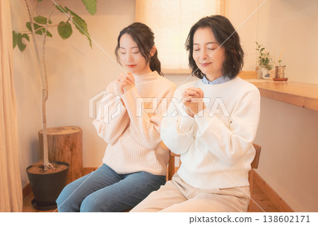 A mother and daughter praying for the deceased at home (retro style) A mother and daughter praying for the deceased at home (retro style) 138602171