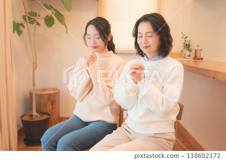 A mother and daughter praying for the deceased at home (retro style) A mother and daughter praying for the deceased at home (retro style) 138602172