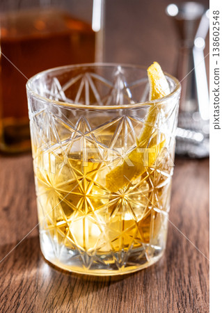 Rusty Nail Cocktail with Lemon Peel in Crystal Glass 138602548
