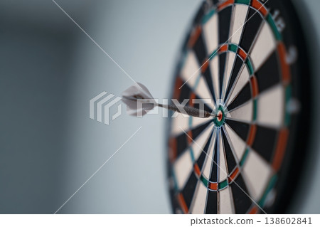Dart hitting bullseye on dartboard close up 138602841