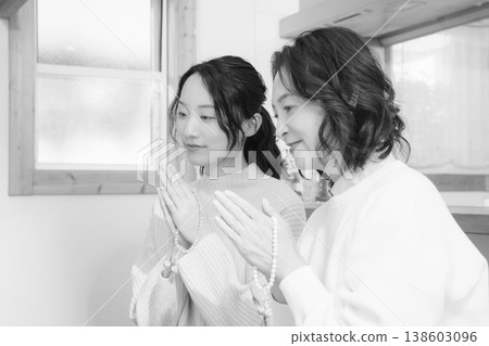 A mother and daughter pray for the deceased at home (black and white) 138603096