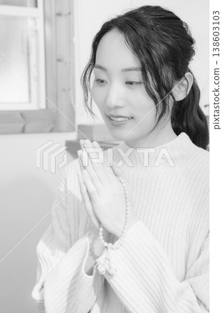 A daughter prays for her deceased loved one at home (black and white) 138603103