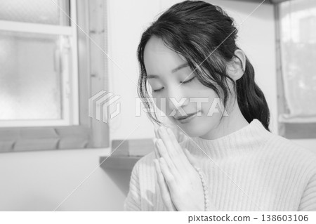 A daughter prays for her deceased loved one at home (black and white) A daughter prays for her deceased loved one at home (black and white) 138603106