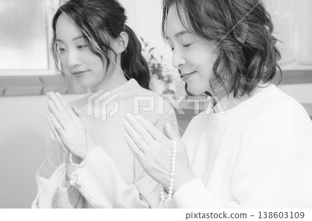 A mother and daughter pray for the deceased at home (black and white) A mother and daughter pray for the deceased at home (black and white) 138603109