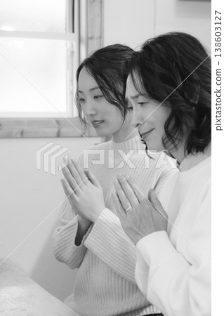 A mother and daughter pray for the deceased at home (black and white) 138603127