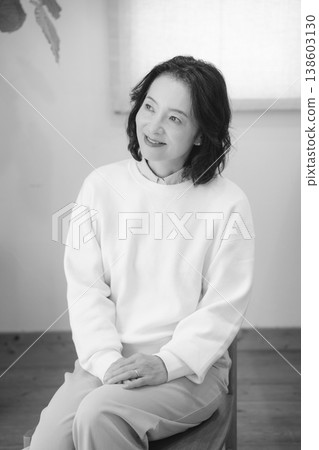 A middle-aged woman after offering prayers for the deceased at home (black and white) A middle-aged woman after offering prayers for the deceased at home (black and white) 138603130