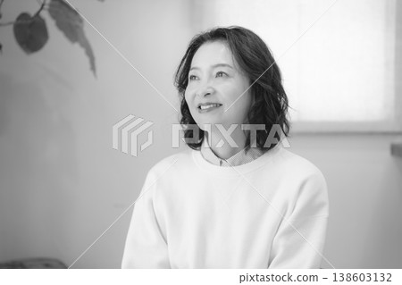 A middle-aged woman after offering prayers for the deceased at home (black and white) A middle-aged woman after offering prayers for the deceased at home (black and white) 138603132