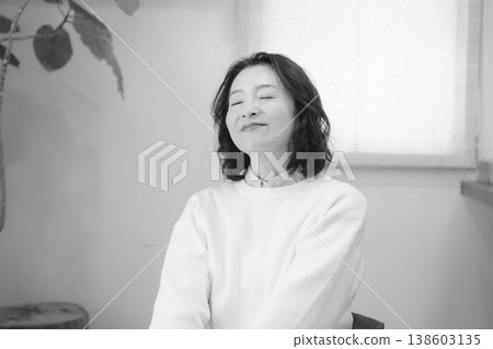 A middle-aged woman after offering prayers for the deceased at home (black and white) A middle-aged woman after offering prayers for the deceased at home (black and white) 138603135