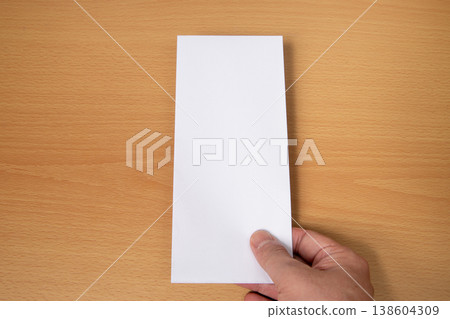 He hands over the envelope he is holding in his right hand. 138604309