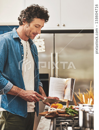 Recipe, food and man cutting vegetables in the kitchen for diet, healthy or nutrition dinner. Book, cooking and mature male person from Canada chop ingredients for a supper or lunch meal at home. 138604716