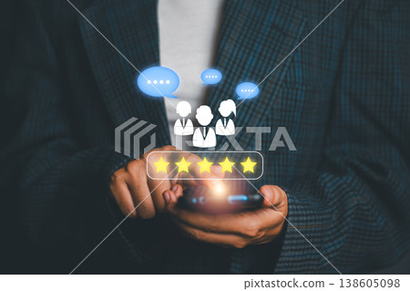Close-up of a person in a suit using a smartphone with digital icons representing customer feedback and ratings. 138605098