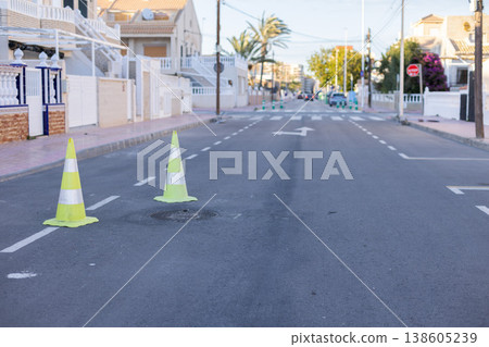 Yellow green cones with a white stripe on the asphalt road. Drive safety and constructions concept. Yellow green cones with a white stripe on the asphalt road. Drive safety and constructions concept. 138605239