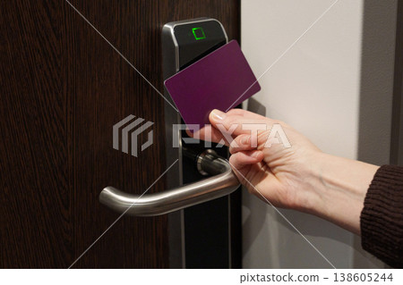 Hand using key card to unlock hotel room door Hand using key card to unlock hotel room door 138605244
