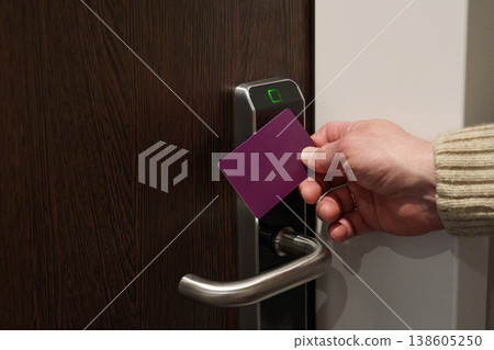 Hand using key card to unlock hotel room door 138605250