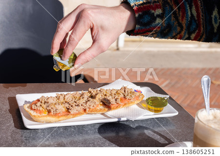 Man drizzling tostada with olive oil. Spanish breakfast. 138605251
