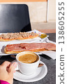 Woman drinking coffee with milk and eating tostada in a cafe outside. 138605255